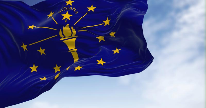 The Indiana State Flag waving against a blue sky