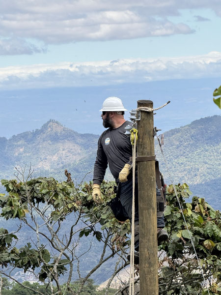 A man gazes at a mountain view on a utility pole in Guatemala.