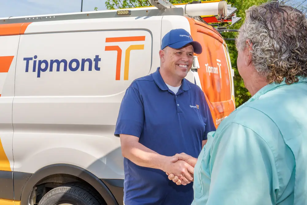A Tipmont fiber installer introduces himself to a customer near a Tipmont van